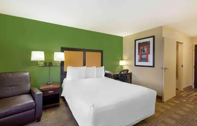 a hotel room with a large bed and a chair at Extended Stay America Suites - Cleveland - Brooklyn in Brooklyn