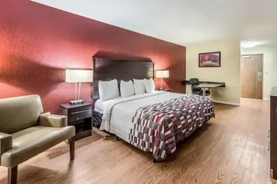 a hotel room with a bed and a chair at Red Roof Inn & Suites Wapakoneta in Wapakoneta