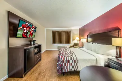 a hotel room with a bed and a flat screen tv at Red Roof Inn & Suites Wapakoneta in Wapakoneta
