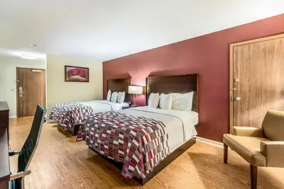 a hotel room with two beds and a chair at Red Roof Inn & Suites Wapakoneta in Wapakoneta