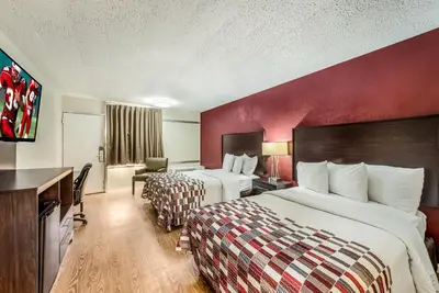 a hotel room with two beds and a desk at Red Roof Inn & Suites Wapakoneta in Wapakoneta