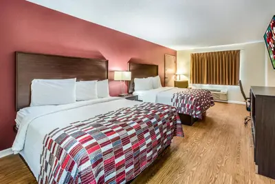 two beds in a hotel room with red walls at Red Roof Inn & Suites Wapakoneta in Wapakoneta
