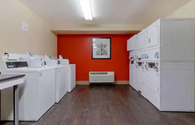 a room with white washing machines and an orange wall at Extended Stay America Suites - Columbus - NE - I-270 in Gahanna