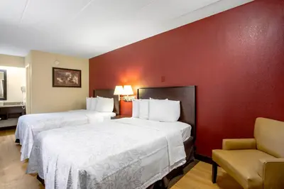 a hotel room with two beds and a chair at Red Roof Inn PLUS+ Columbus - Dublin in Dublin