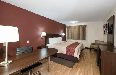 a hotel room with a bed and a desk at Red Roof Inn Toledo - Maumee in Maumee