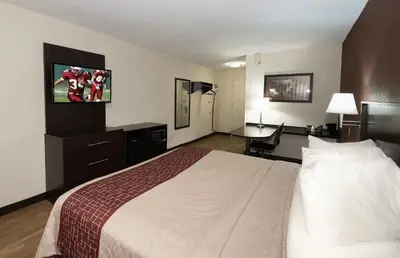 a hotel room with a bed and a flat screen tv at Red Roof Inn Toledo - Maumee in Maumee
