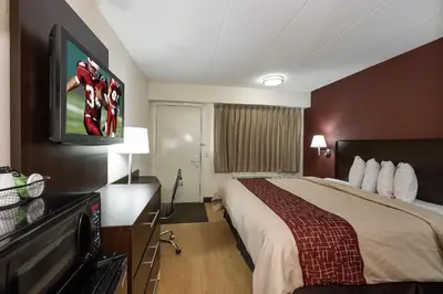 a hotel room with a bed and a flat screen tv at Red Roof Inn Toledo - Maumee in Maumee