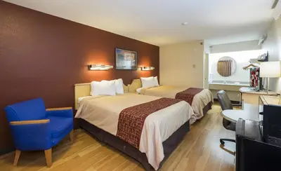 a hotel room with two beds and a blue chair at Red Roof Inn Cincinnati - Sharonville in Sharonville