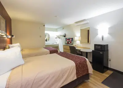 a hotel room with two beds and a desk at Red Roof Inn Cincinnati - Sharonville in Sharonville