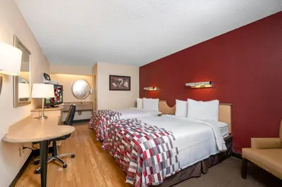 a hotel room with a large bed with a red wall at Red Roof Inn Cleveland - Mentor/ Willoughby in Willoughby