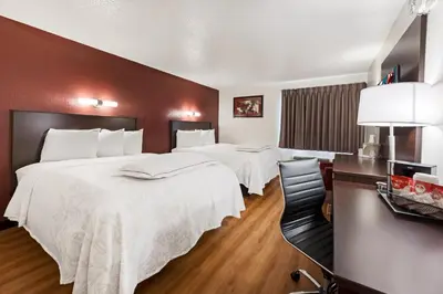 a hotel room with two beds and a table at Red Roof Inn PLUS+ Columbus - Worthington in Columbus