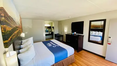 a hotel room with a large bed and a mirror at Days Inn by Wyndham Maysville Kentucky in Maysville