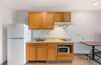 a kitchen with wooden cabinets and a white refrigerator at Extended Stay America Select Suites - Cleveland - Avon in Avon