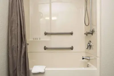 a bathroom with a tub and a shower with a shower curtain at Suburban Studios Mentor - Cleveland Northeast in Mentor