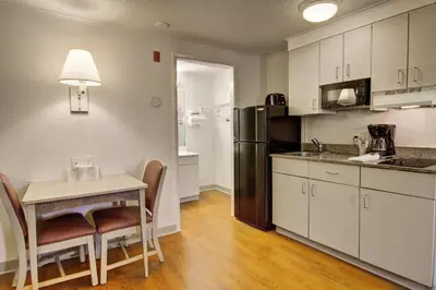 a kitchen with a small table and a refrigerator at Suburban Studios Mentor - Cleveland Northeast in Mentor