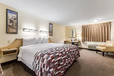 a hotel room with a bed and a chair at Red Roof Inn Cleveland Airport - Middleburg Heights in Middleburg Heights
