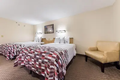 a hotel room with two beds and a chair at Red Roof Inn Cleveland Airport - Middleburg Heights in Middleburg Heights