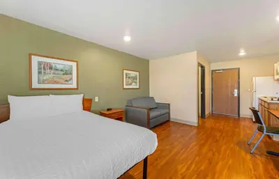 a bedroom with a bed and a chair and a kitchen at Extended Stay America Select Suites - Cleveland - Mentor in Mentor