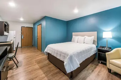 a bedroom with a bed and a blue wall at WoodSpring Suites Columbus West - Hilliard in Hilliard