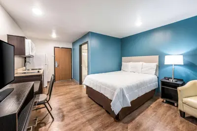 a bedroom with a bed and a blue wall at WoodSpring Suites Columbus West - Hilliard in Hilliard