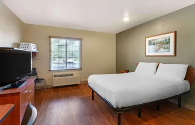 a bedroom with a bed and a flat screen tv at Extended Stay America Select Suites - Akron - South in Portage Lakes