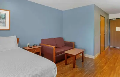a bedroom with a bed and a chair and a table at Extended Stay America Select Suites - Akron - South in Portage Lakes