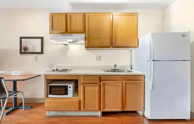 a kitchen with wooden cabinets and a white refrigerator at Extended Stay America Select Suites - Cincinnati - Florence - Airport in Florence