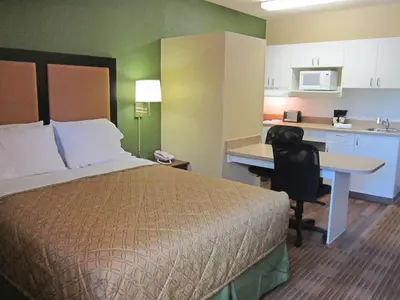 a hotel room with a bed and a desk and a kitchen at Extended Stay America Suites - Toledo - Holland in Holland