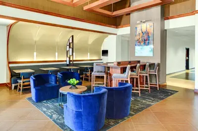 a lobby of a hotel with blue chairs and tables at Hyatt Place Cincinnati Airport in Florence