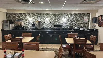 a restaurant with tables and chairs and a brick wall at Rodeway Inn in Barboursville