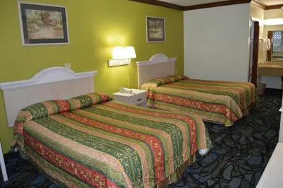 two beds in a hotel room with green walls at Economy Inn Cuyahoga Falls in Cuyahoga Falls