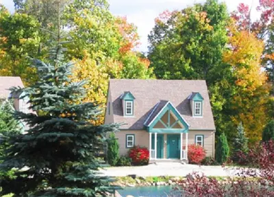 a house with a tree in front of it at Spruce Hill Inn & Cottages in Mansfield