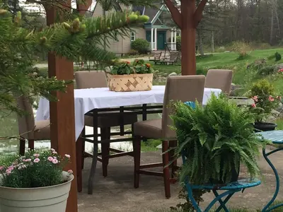 a table with chairs and potted plants on a patio at Spruce Hill Inn & Cottages in Mansfield