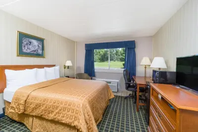 a hotel room with a bed and a television at Days Inn by Wyndham Columbus East Airport in Columbus
