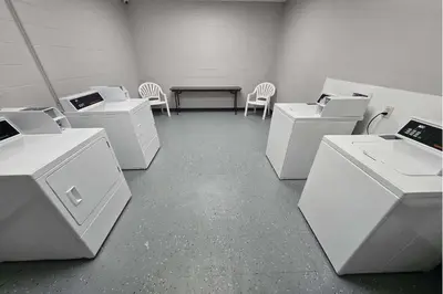 a room with white washing machines and a table and chairs at Days Inn by Wyndham Columbus East Airport in Columbus