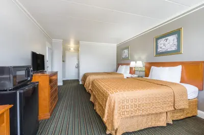 a hotel room with two beds and a flat screen tv at Days Inn by Wyndham Columbus East Airport in Columbus