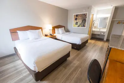 a hotel room with two beds and a desk at Days Inn by Wyndham Florence Cincinnati Area in Florence