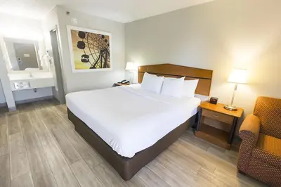 a hotel room with a large bed and a chair at Days Inn by Wyndham Florence Cincinnati Area in Florence