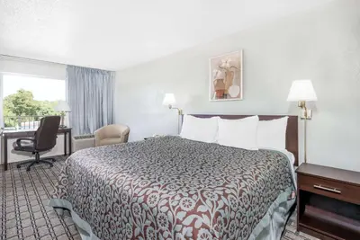 a hotel room with a bed and a desk and a window at Days Inn by Wyndham St Clairsville in Saint Clairsville