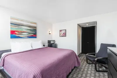 a hotel room with a purple bed and a chair at Days Inn by Wyndham St Clairsville in Saint Clairsville