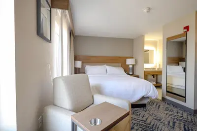 a hotel room with a bed and a chair at Candlewood Suites Beachwood Cleveland by IHG in Beachwood