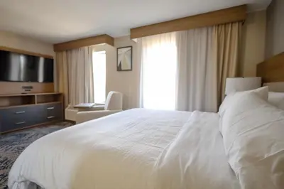 a bedroom with a large white bed and a television at Candlewood Suites Beachwood Cleveland by IHG in Beachwood