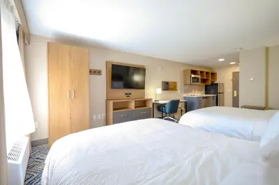 a hotel room with two beds and a desk at Candlewood Suites Beachwood Cleveland by IHG in Beachwood