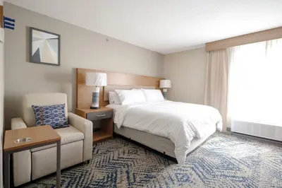a hotel room with a bed and a chair at Candlewood Suites Beachwood Cleveland by IHG in Beachwood