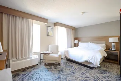 a hotel room with a bed and a chair at Candlewood Suites Beachwood Cleveland by IHG in Beachwood