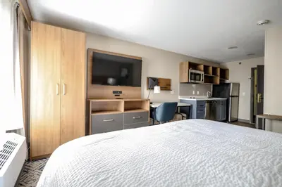 a bedroom with a bed and a desk with a television at Candlewood Suites Beachwood Cleveland by IHG in Beachwood