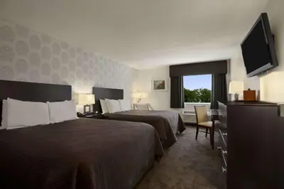 a hotel room with two beds and a flat screen tv at Travelodge by Wyndham Hubbard OH in Hubbard