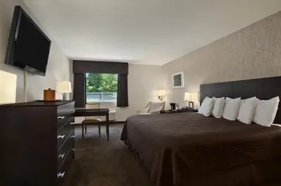 a hotel room with a bed and a flat screen tv at Travelodge by Wyndham Hubbard OH in Hubbard
