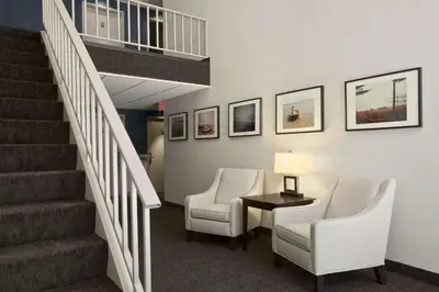 a lobby with two chairs and a stair case at Travelodge by Wyndham Hubbard OH in Hubbard