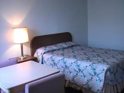 a bedroom with a bed and a table with a lamp at Hometown Inn Galion in Galion